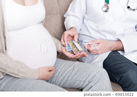 Doctor is giving pills to a pregnant woman and explaining how to use them. Treatment during pregnancy 69853022