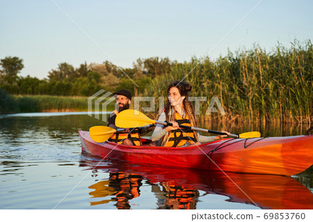 Couple of kayakers swimming during sunset 69853760