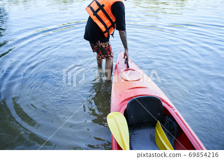 Man in safe jacket pulling canoe Man in safe jacket pulling canoe 69854216
