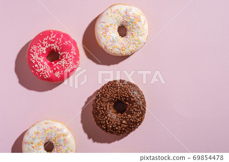 Chocolate, pink and vanilla donuts with sprinkles, sweet glazed dessert food on pink minimal background, top view copy space 69854478
