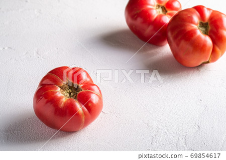 Three pink heirloom tomato vegetables, fresh red ripe tomatoes, vegan food, white stone concrete background, angle view selective focus 69854617