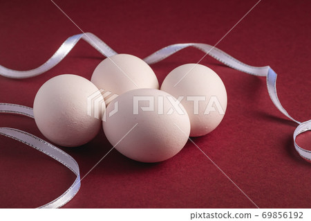 White eggs with fabric ribbon on red paper background, happy Easter day White eggs with fabric ribbon on red paper background, happy Easter day 69856192
