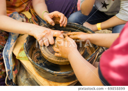 A close up view on ceramic production process on potter's wheel with children. Clay crafts with kids concept 69858899
