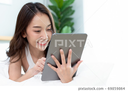 Asian woman shopping online on tablet.Check and working online. Asian woman shopping online on tablet.Check and working online. 69859864