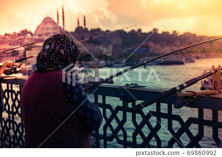 Old woman fishing on Galata bridge. Vacation in Istanbul. 69860992