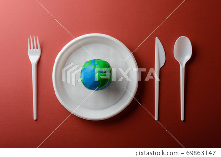 Serving table with Earth planet, plastic plate, spoon, fork and knife. Ecology Concept for Earth Hour, Earth Day, Ocean Day and other ECO dates. 69863147