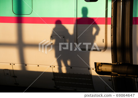 Shadows of two people leaving for a trip reflected on the train 69864647