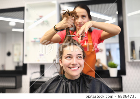 Female client sits in chair in hairdressing salon. 69864733
