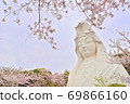 Ofuna Kannon statue surrounded by blue sky and bright cherry blossoms 69866160