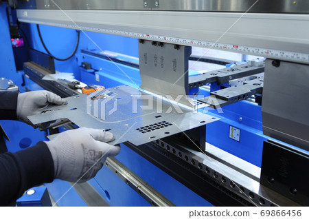 Worker hands holding the metal sheet working with the CNC hydraulic press brake machine 69866456