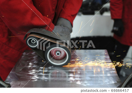 Worker hands sanding metal sheet by the hand held belt sender 69866457