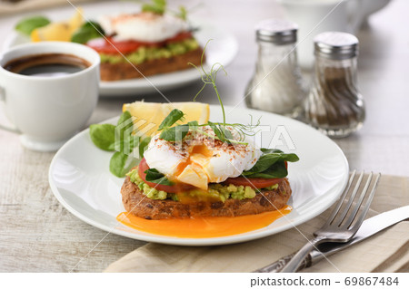Eggs Benedict with guacamole on cereal bread 69867484