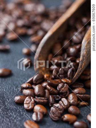 Fresh raw coffee beans in woode scoop on black. 69867609