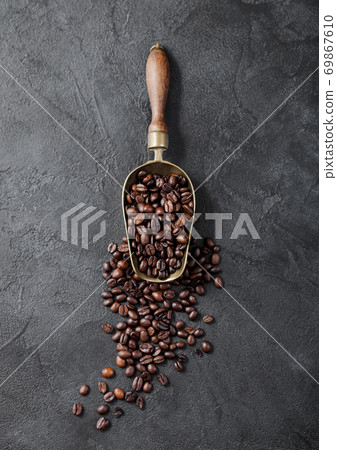 Fresh raw organic coffee beans in vintage steel scoop on black. 69867610