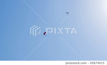 Tandem parachute jump. Silhouette of skydiver flying in blue clear sky. Tandem parachute jump. Silhouette of skydiver flying in blue clear sky. 69874633