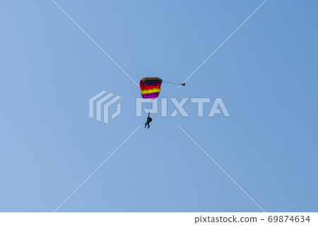 Tandem parachute jump. Silhouette of skydiver flying in blue clear sky. Tandem parachute jump. Silhouette of skydiver flying in blue clear sky. 69874634