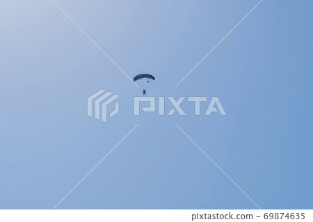 Tandem parachute jump. Silhouette of skydiver flying in blue clear sky. Tandem parachute jump. Silhouette of skydiver flying in blue clear sky. 69874635