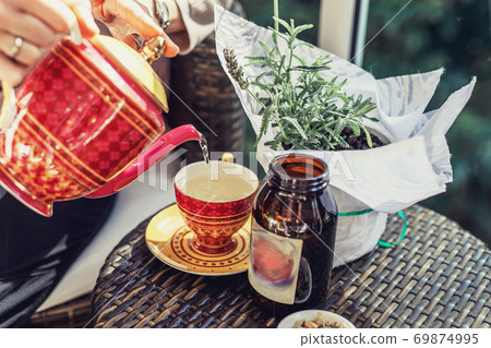 Woman's hand pouring tea from teapot to cup Woman's hand pouring tea from teapot to cup 69874995