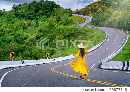 Woman walking on road no.3 or sky road over top of mountains with green jungle in Nan province, Thailand. Woman walking on road no.3 or sky road over top of mountains with green jungle in Nan province, Thailand. 69877748
