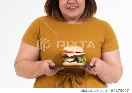 Hungry overweight young Asian woman holding hamburger on isolated background, Her hungry all time and overeat, gluttony and binge eating. Her lifestyle is eating fast food all time. Unhealthy Concept Hungry overweight young Asian woman holding hamburger on isolated background, Her hungry all time and overeat, gluttony and binge eating. Her lifestyle is eating fast food all time. Unhealthy Concept 69878097