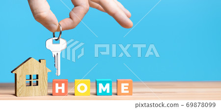 Real estate agent's hand hold key above house model on blue background. Real estate agent's hand hold key above house model on blue background. 69878099