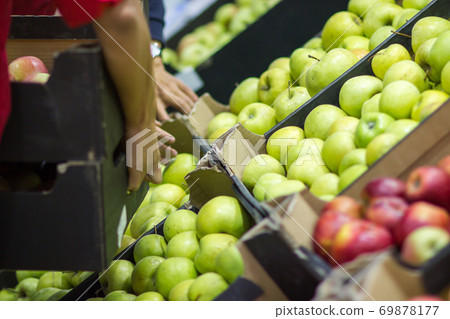 Young man seller lays out fresh fruits of the box on the grocery store 69878177