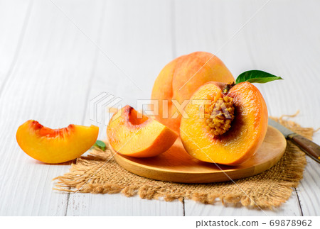 Fresh sweet sliced peach with green leaf on wood plate 69878962