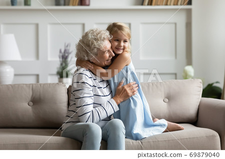 Adorable preschool girl holding arms around neck of mature grandmother 69879040