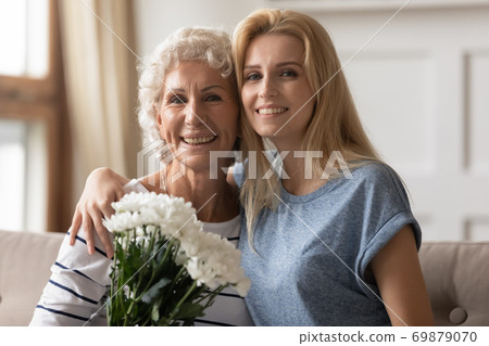 Smiling old lady retired professor receiving flowers from former student 69879070