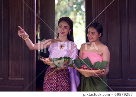 Asian woman wearing Thai dress costume traditional according culture and tradition cooking in the kitchen at the ancient house Ayutthaya, Thailand Asian woman wearing Thai dress costume traditional according culture and tradition cooking in the kitchen at the ancient house Ayutthaya, Thailand 69879295