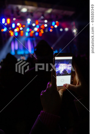 A girl is taking pictures of a street concert  69880349