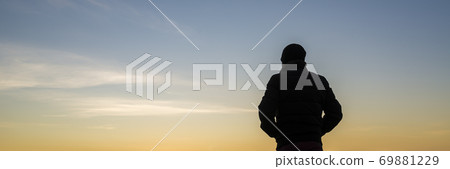 Wide backlit view on person with hands in pockets Wide backlit view on person with hands in pockets 69881229
