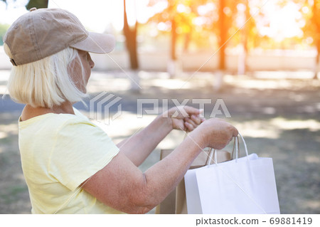 Caucasian blond female delivery man courier holds paper bags with groceries to send to customer home. Commercial delivery concept 69881419