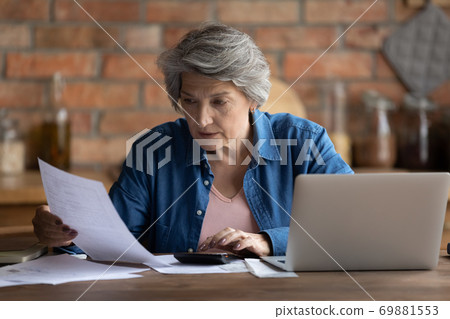Mature 60s woman manage household finances at home Mature 60s woman manage household finances at home 69881553