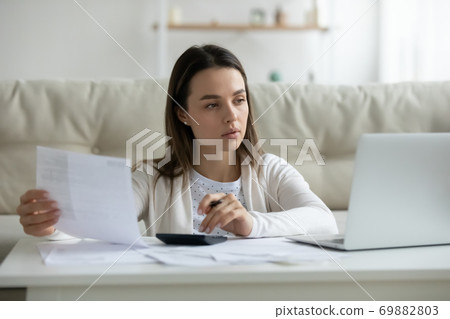 Young woman manage household budget paying on laptop Young woman manage household budget paying on laptop 69882803