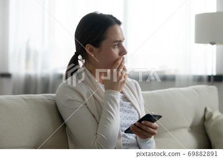 Worried young woman distressed with cellphone message Worried young woman distressed with cellphone message 69882891
