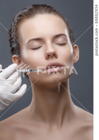 The doctor cosmetologist makes the Rejuvenating facial injections procedure for tightening and smoothing wrinkles on the face skin of a women in a beauty salon. Cosmetology skin care The doctor cosmetologist makes the Rejuvenating facial injections procedure for tightening and smoothing wrinkles on the face skin of a women in a beauty salon. Cosmetology skin care 69882934