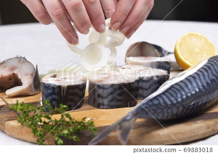 the chef's hand sprinkles onions on mackerel with lemon the chef's hand sprinkles onions on mackerel with lemon 69883018