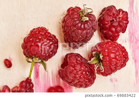 Several berries of red ripe raspberries on a wooden background 69883422