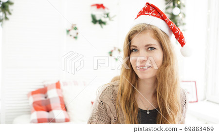 Portrait of attractive smiling woman in Christmas hat at nome 69883469