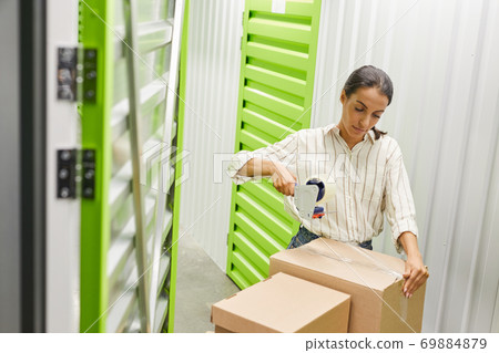 Woman Packing Boxes in Storage Facility 69884879