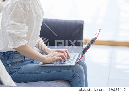 A woman using a computer on the sofa without a face 69885442