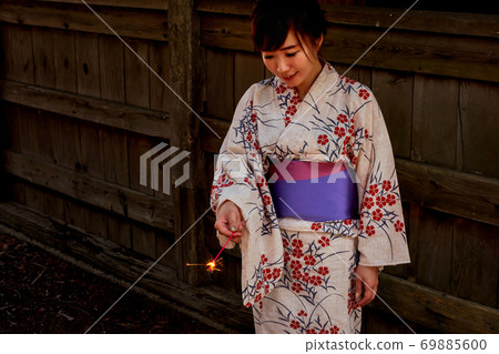 A woman in a yukata with fireworks 69885600