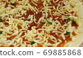 Cooking pizza. Chef put cheese and basil on the base of the pizza greased with tomato paste. A man 69885868