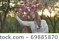 Girl makes selfie in the garden. An attractive red-haired woman smiles making selfi using a mobile 69885870