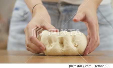 woman on the kitchen table makes domestic food pizza, hands work and pushing stir knead the dough woman on the kitchen table makes domestic food pizza, hands work and pushing stir knead the dough 69885890