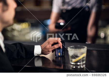 the man pays the bartender for the order with a credit card the man pays the bartender for the order with a credit card 69886326