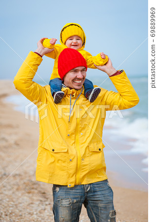 Dad with a baby on the seashore in colorful clothes. Dad with a baby on the seashore in colorful clothes. 69889969