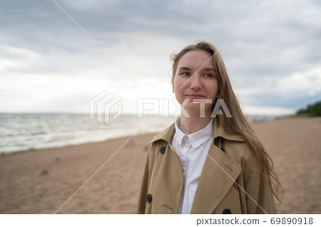 pretty girl walking on a beach in beige trench coat pretty girl walking on a beach in beige trench coat 69890918
