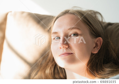 young woman relaxing on a couch with sunlight from a window 69891035